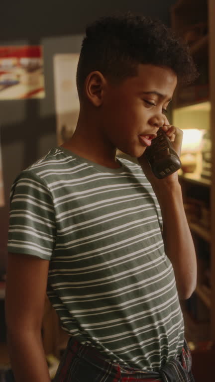 Vertical of Black Boy Calling Parents or Friend Using Retro Handset in 90s