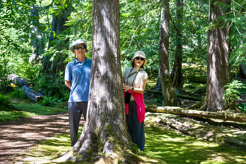 Couple walking in the forest and posing for photos in dappled sunlight. Seattle. USA.
