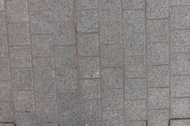 Surface of pavement made of gray unpolished granite stone blacks