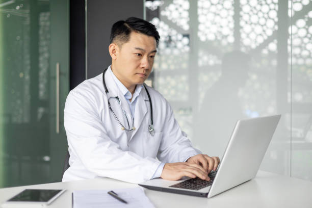 istock Asian mature doctor working on laptop in modern office 2151075426