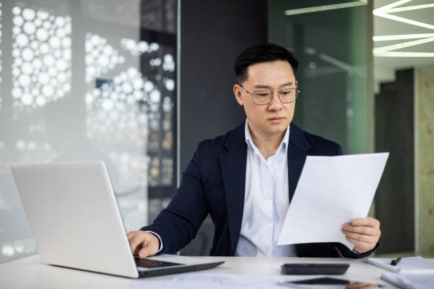 istock Focused businessman reviewing documents in modern office 2151075511