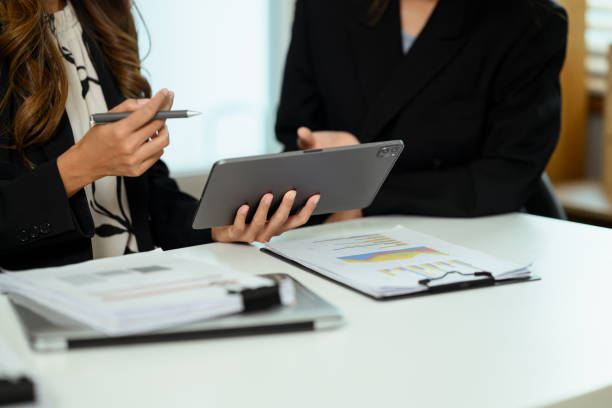 istock Cropped shot of businesswoman discussing work issues and using digital tablet at office table 2151075524