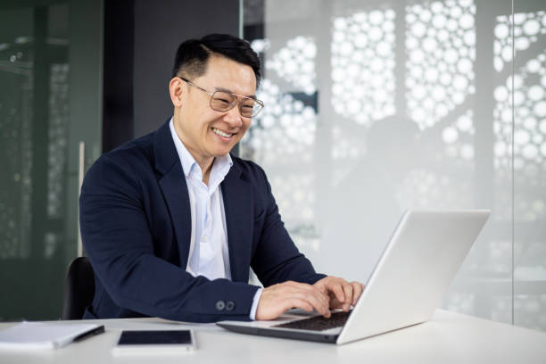 istock Happy Asian businessman using laptop in modern office 2151076520