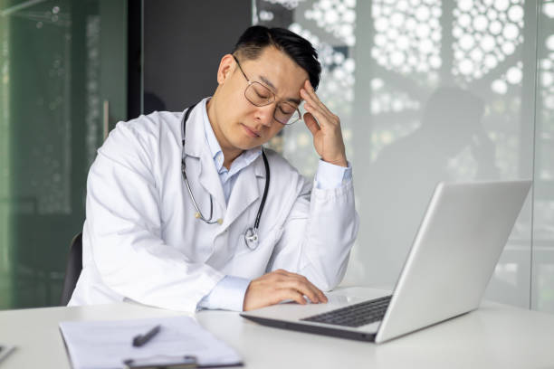 Stressed Asian doctor feeling tired in his office
