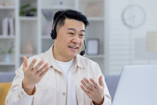 istock Smiling Asian man working from home with headset on 2151077218