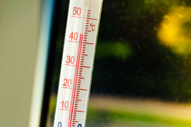 Celsius thermometer on window shows high temperature during heat waves outside. Summer temperatures, climate change.