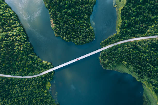 Aerial view of bridge asphalt road with cars and blue water lake and green woods Aerial view of bridge asphalt road with cars and blue water lake and green woods in Finland. drone car on road stock pictures, royalty-free photos & images