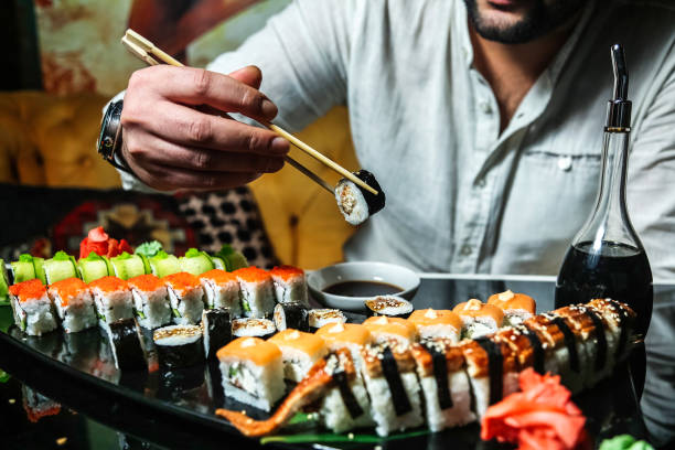 istock Man Holding Chopsticks Over Tray of Sushi 2151080714