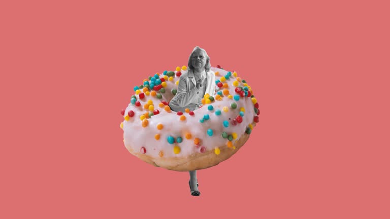 Stop motion. Animation. Woman in a suit dancing standing in donut isolated over pink background. Retro style