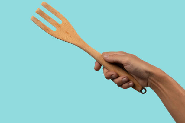 istock Hand holding wooden cooking fork on cyan background 2151080911