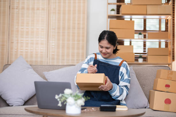 istock entrepreneurs small business Write shipping information on a cardboard box in home office. Small business operators preparing to ship to customer 2151087626