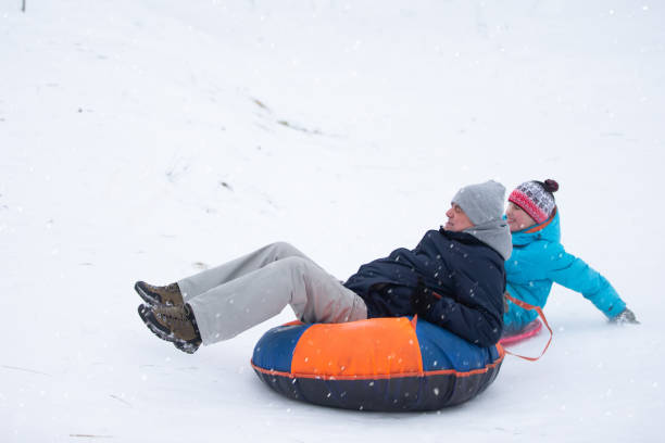 istock Dad and son roll down a snow slide on a tubing. 2151089418