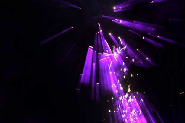 On a dark background, purple lazar rays from stage spotlights.