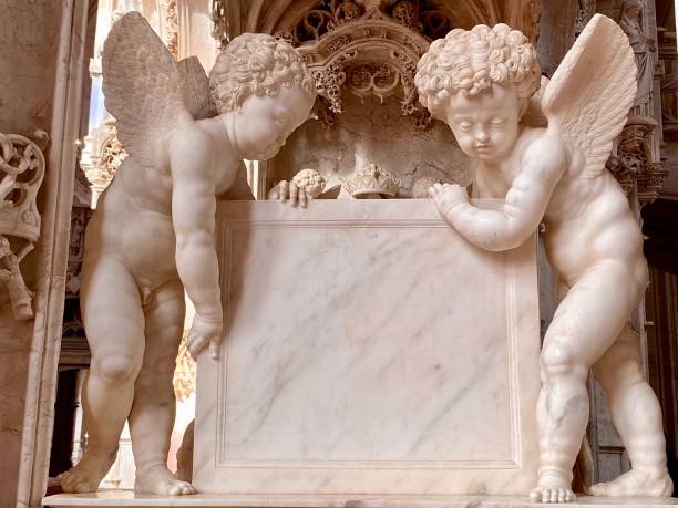 Close up of marble statue back of head of small child, cherub, showing curly hair detail. Cathedral wall with prism light effect in background. High quality photo