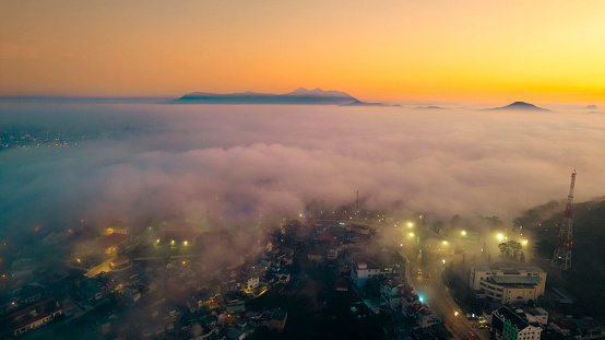 A city emerges from a sea of fog in the early morning light, at Dalat city, Vietnam