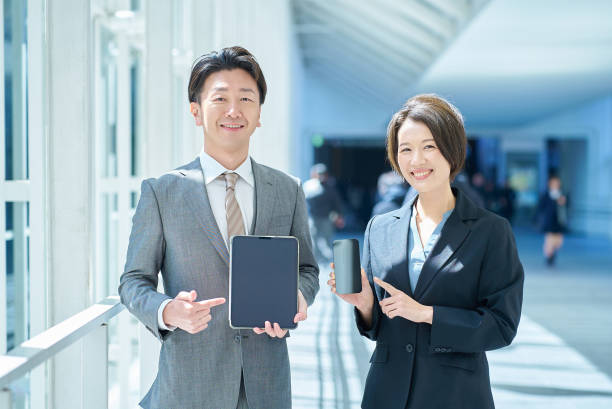 istock A man and a woman in suits holding digital devices 2151094548
