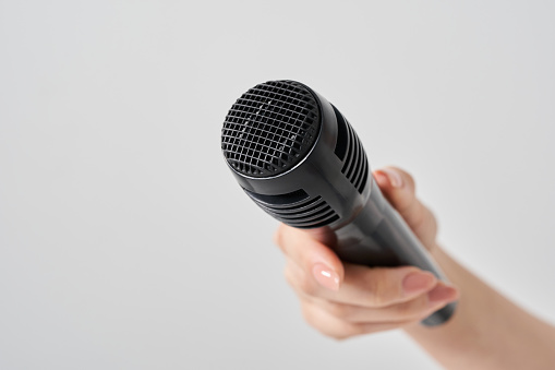 Woman's hand holding a wireless microphone and white background