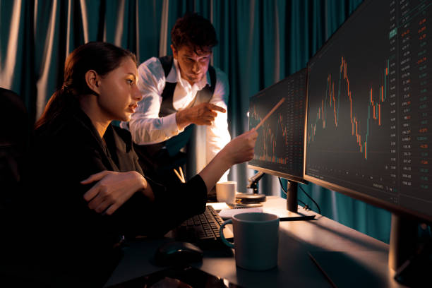 istock Two business traders discussing on dynamic stock exchange at night. Postulate. 2151101272