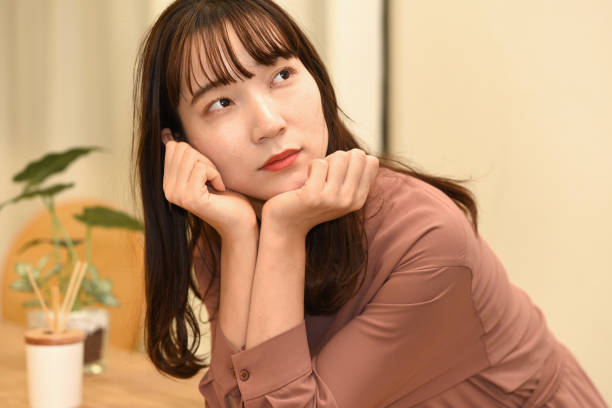 istock A young beautiful Asian woman is thinking about things with an anxious face. 2151104800