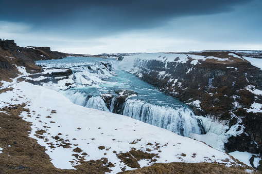 Powerful Gullfoss waterfall flowing in Hvita river canyon during winter in gloomy day at Southwest Iceland
