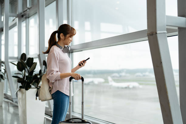 istock Young woman using smartphone in airport 2151122847
