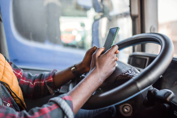 istock Unrecognizable male truck driver uses mobile phone to surf internet while taking a break from driving 2151127811