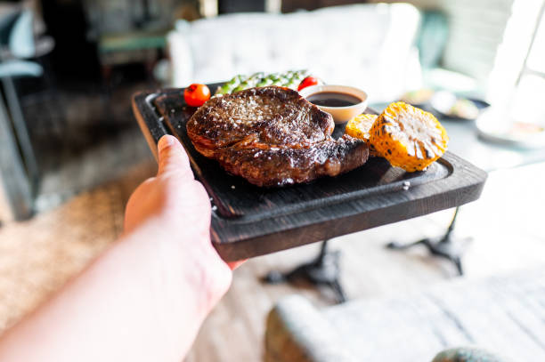 hand hold Grilled beef steak with sauce in plate