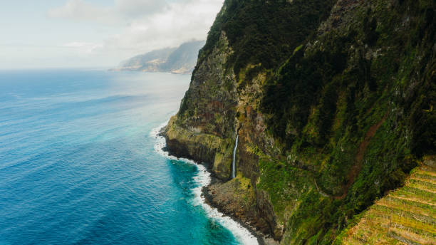 istock Dramatic Aerial View of Waterfall Falling From Mountains Into Ocean 2151129914