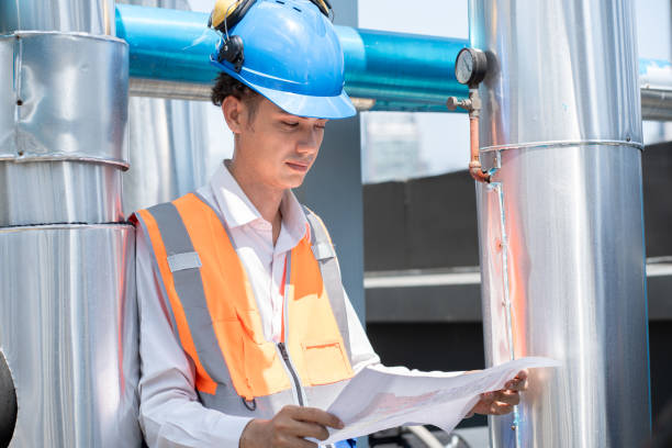 istock Portrait Asia male engineer in protective workwear is performing a conducts system check with use paperwork at rooftop building 2151138435
