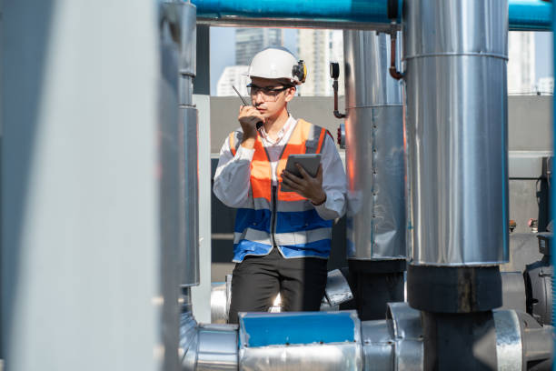 istock Portrait Asia male engineer in protective workwear is performing a conducts system check with use tablet computer and walkie talkie at rooftop building 2151138496