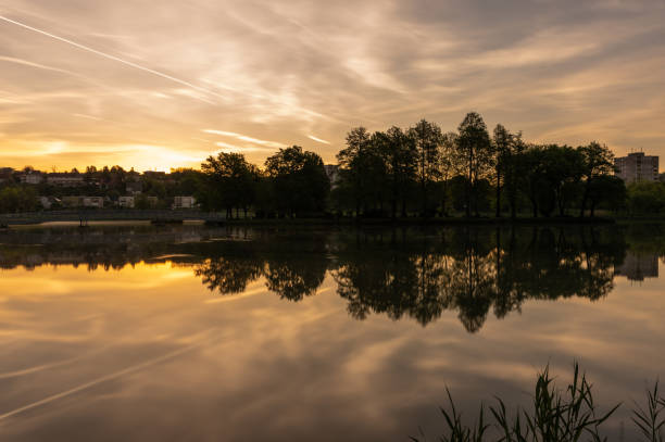 Long exposure shot of the Boating Lake with houses in the background in Ajka at sunrise on springtime.