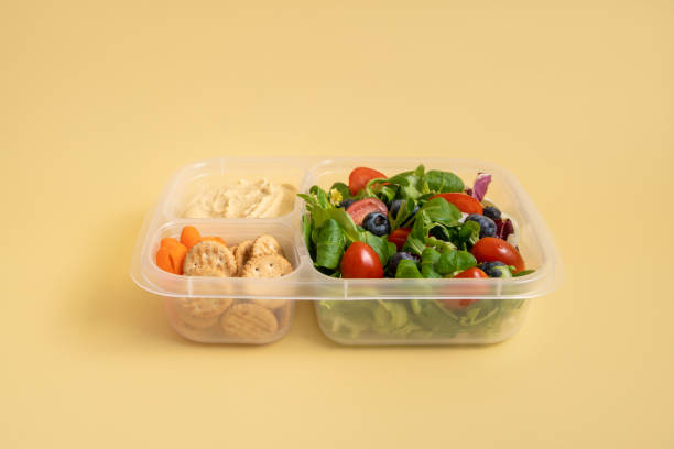 istock Lunch box with salad and hummus on yellow background 2151142223