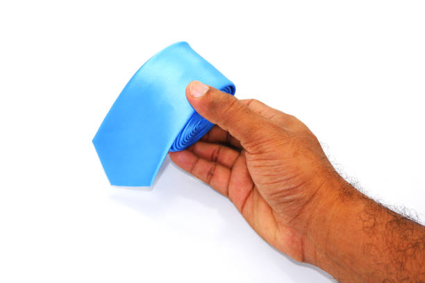 istock A blue necktie rolled on white background close-up view touching by human hand 2151144825