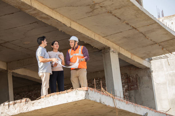 istock Architect explaining blueprint to couple at construction building 2151146514