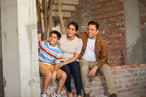 Happy family sitting on brick wall at construction site