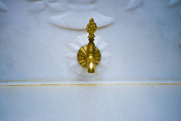 A luxurious golden fountain tap adorned with intricate white marble designs, exuding elegance and opulence.