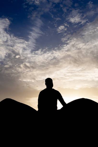 istock backlit shot of isolated man meditating at wall with sunset dramatic sky at dusk 2151150064