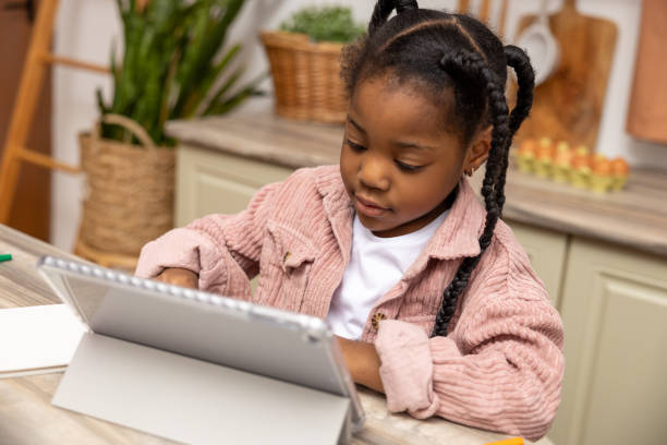 istock Little girl browsing internet on her tablet exploring educational websites for her school project 2151152843