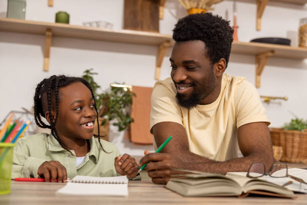istock Cheerful black dad with his daughter doing school tasks 2151153023