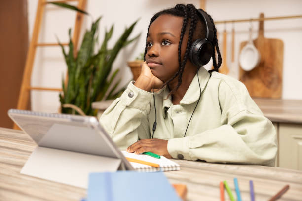 istock Pensive little African American girl doing home work using digital tablet 2151153141