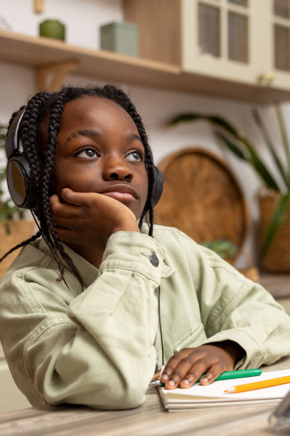 istock Pensive little African American girl doing home work using digital tablet 2151153142