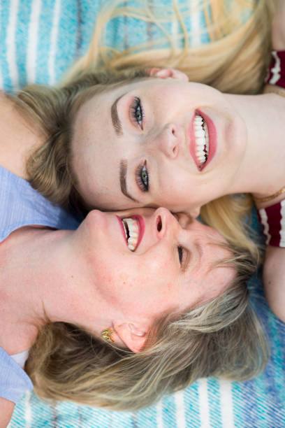 Tender sunset moment between mother and teenage daughter touching foreheads, their faces glowing in warm evening light and surrounded by soft strands of hair. High quality photo
