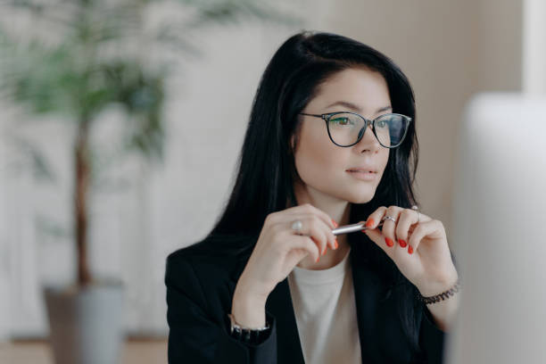 istock Thoughtful businesswoman with pen in hand, deeply focused on her work task. 2151157735