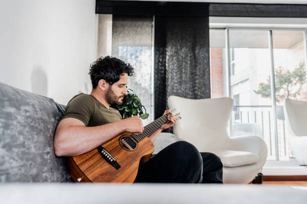 istock Mid adult man playing guitar at home 2151158963