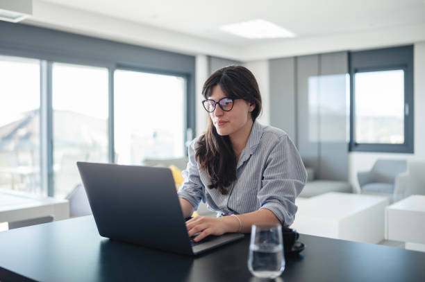 istock Young woman using laptop on table at home. 2151159525