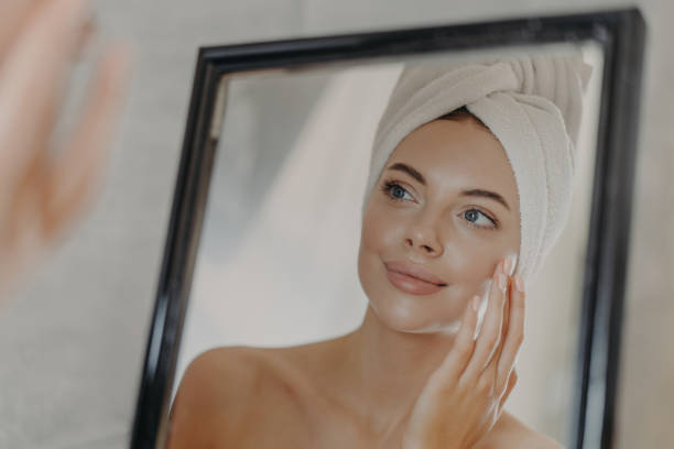 istock Woman examines her reflection with care, poised during a tranquil skincare routine. 2151159619