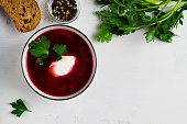 beetroot soup in bowl with parsley. delicious borscht with sour cream, green parsley, garlic on the white background. top view. Traditional Russian and Ukrainian dish. copy space.