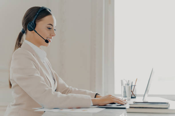 istock Composed professional uses laptop for communication, headset in a white office. 2151159869