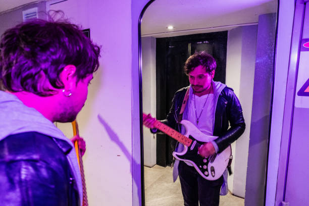 Mid adult man playing guitar in front of mirror