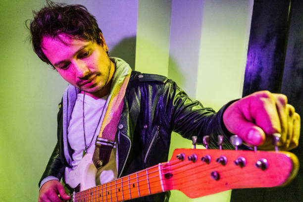 Mid adult man tuning guitar indoors